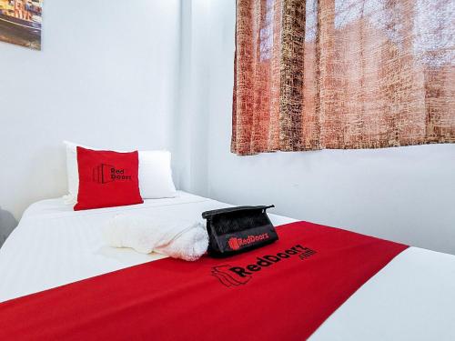 a bed with a red blanket and a hat on it at RedDoorz near Notre Dame of Dadiangas University in General Santos