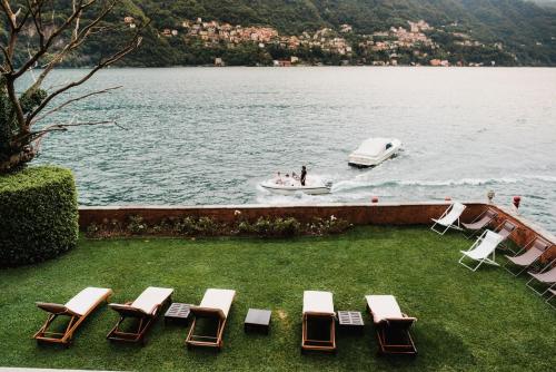 a group of chairs and a boat in the water at Regina Teodolinda Suites in Laglio