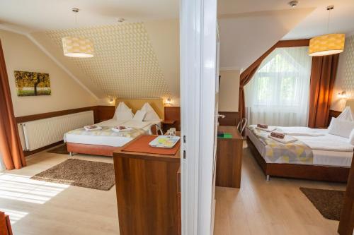 1 Schlafzimmer mit 2 Betten und einem Schreibtisch in einem Zimmer in der Unterkunft Hotel Pávai in Hajdúszoboszló