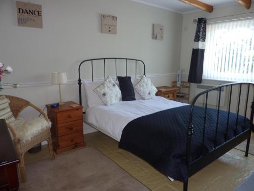 a bedroom with a large bed and a chair at Banfield Lodge for Gower in Swansea