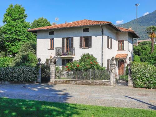 a large white house with a fence in a yard at VILLA LAGO foreground - Pet friendly stay- garden-parking-Lake view- Bike friendly holiday house in Colico
