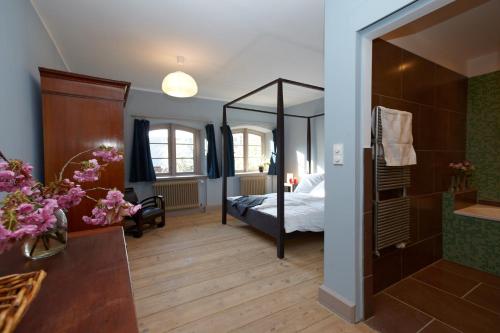 a bathroom with a bedroom with a bed and a mirror at Gutshaus Lexow in Lexow