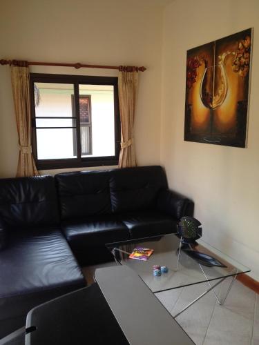 a living room with a black leather couch and a glass table at Paradis Villa B3 in Ko Kho Khao
