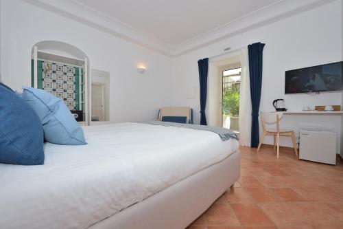 a bedroom with a large white bed with blue pillows at Casa Amorino in Minori