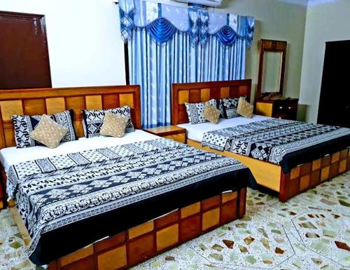 two beds in a bedroom with blue curtains at Gulshan E Jamal Guest House in Karachi