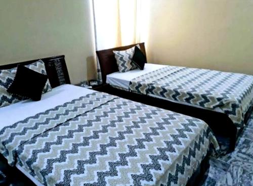 two beds in a small room with at Gulshan E Jamal Guest House in Karachi