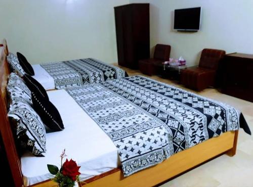 two beds in a room with a room with a tv at Gulshan E Jamal Guest House in Karachi