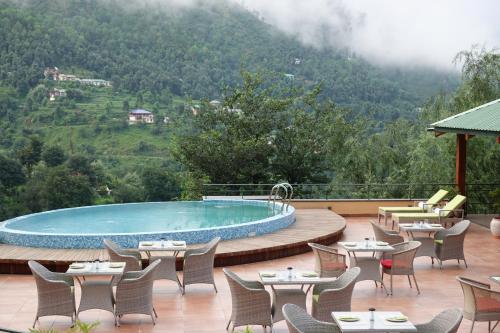 a resort with a pool and tables and chairs at Araiya Palampur in Pālampur