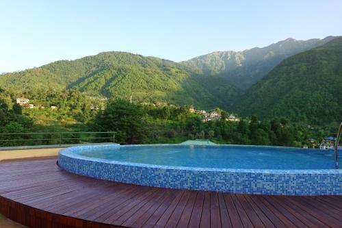 a swimming pool on a deck with mountains in the background at Araiya Palampur in Pālampur