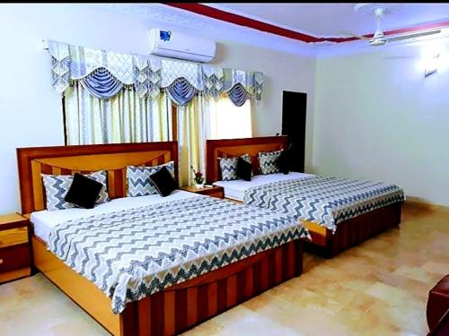 a bedroom with two beds and a window at Gulshan Palace Near Millennium Mall in Karachi