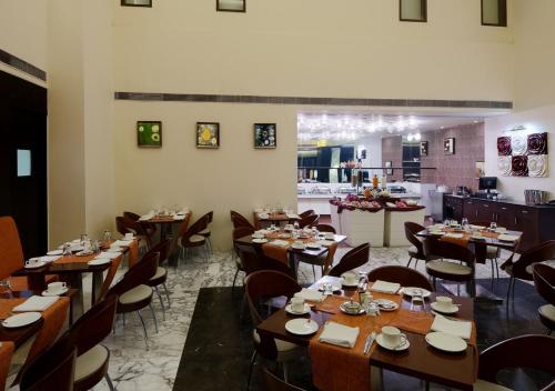 comedor con mesas y sillas de madera en Hotel DS Clarks Inn Gurgaon, en Gurgaon