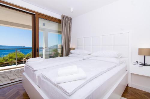 a white bedroom with a large white bed and a window at Villa Stina in Okrug Donji