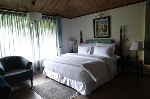 a bedroom with a large white bed and a chair at Araiya Palampur in Pālampur
