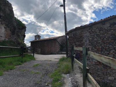 an old brick building with a fence next to a street at Cal Fuste in Torà de Tost
