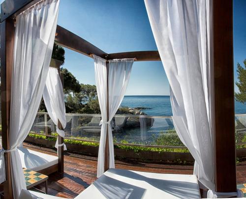 a room with a view of the ocean through curtains at Hotel Cala del Pi - Adults Only in Platja  d'Aro