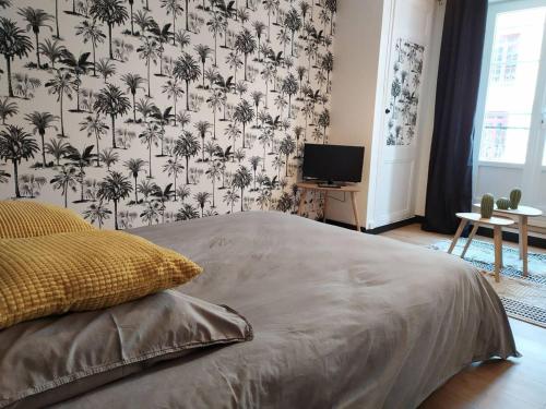 a bedroom with a bed with a wallpaper with palm trees at 1 Emplacement Parfait ! 150m de la mer et de la rue Piétonne in Dieppe