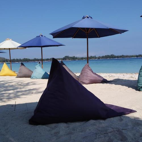 a group of umbrellas and pillows on a beach at Sunset Beach Bungalow in Gili Meno