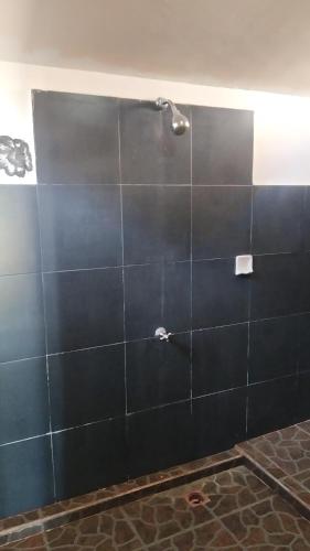 a bathroom with a shower with a black tile wall at Sunset Beach Bungalow in Gili Meno