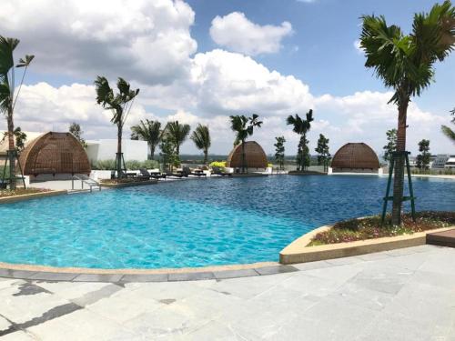 a large swimming pool with palm trees and huts at ALMAS PUTERI HARBOUR in Nusajaya