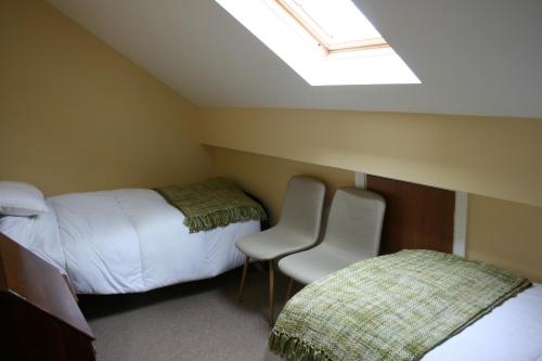 een kamer met 2 bedden en 2 stoelen en een dakraam bij Carrowbruagh in Limavady
