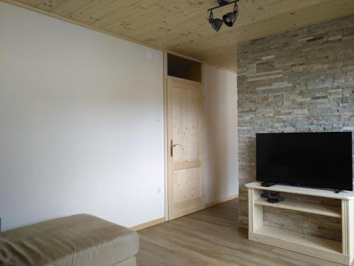un salon avec une télévision à écran plat sur un mur en pierre dans l'établissement Apartmaji Pavc, à Bohinj