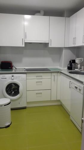 a kitchen with white cabinets and a green floor at Bakio Ocean View in Bakio