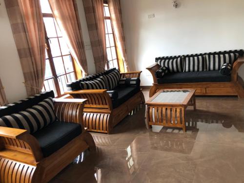a living room with couches and tables and windows at Gimhana Guest House in Nuwara Eliya