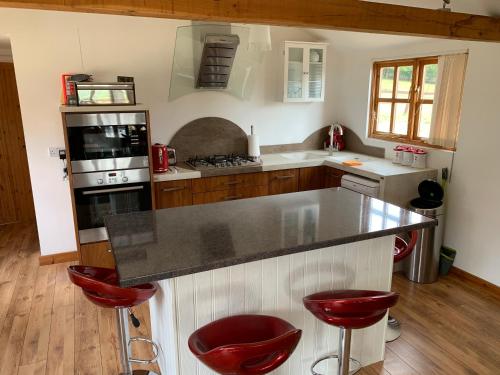 una cocina con encimera y taburetes rojos en Stable lodge 2 Bedrooms, en Horspath
