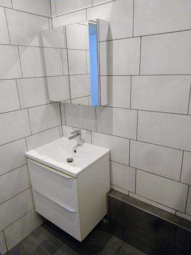 een witte badkamer met een wastafel en een spiegel bij Aux portes de l'Eure in Bonnières-sur-Seine