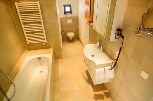 a bathroom with a tub and a sink and a toilet at Lindenhof Hotel Tepe in Damme