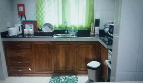 eine Küche mit Holzschränken, einem Waschbecken und einem Fenster in der Unterkunft Destination Self-Catering in Grand'Anse Praslin