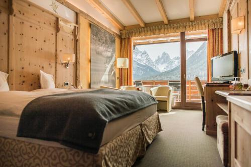 a hotel room with a bed and a large window at Alpenwellnesshotel St. Veit in Sesto