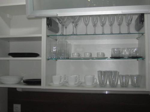 a shelf filled with glasses and cups and bowls at River View Nis - 65 square meters Designer Apartment in heart of city Park for free in Niš
