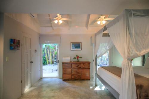 a bedroom with a canopy bed with a dresser and a door at Casa Cecilia Beach Front in Santa Teresa Beach