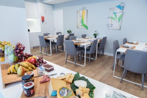 a room with tables and chairs with food on them at Ilha Hostel & Suites in Ponta Delgada
