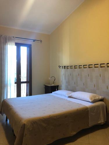 a bedroom with a large white bed with a window at Domus Birdi in Orroli