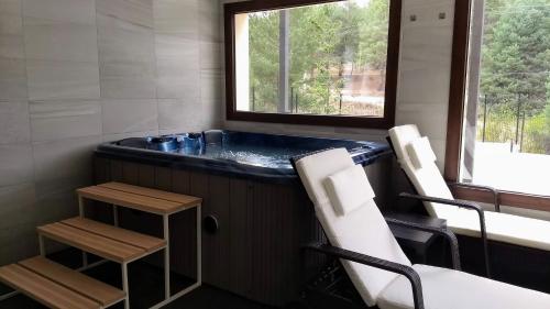 a bathroom with a tub with two chairs and a window at Hotel Rural El Nido de Pinares in Navaleno