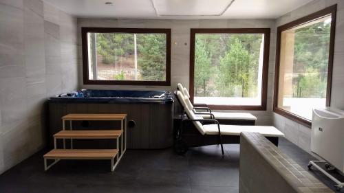 a bathroom with a tub and two windows at Hotel Rural El Nido de Pinares in Navaleno