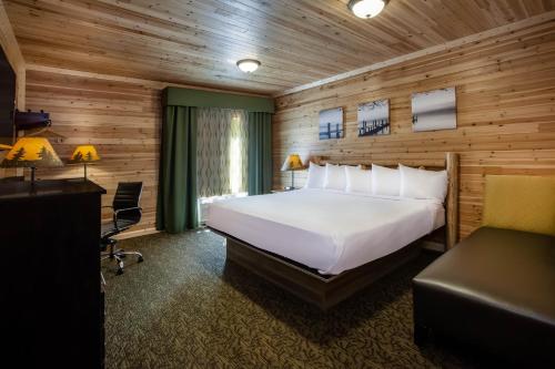 a bedroom with a large white bed and a desk at Days Inn by Wyndham Cadillac in Cadillac
