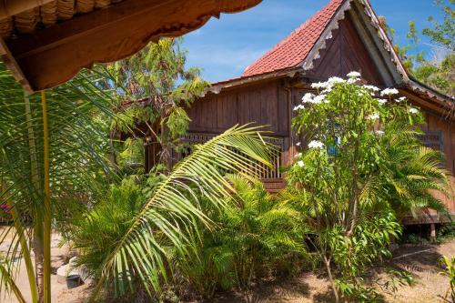 an old house with palm trees in front of it at Palmyra Indah Bungalows in Sekotong