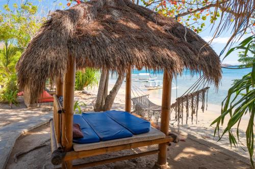 a chair under a straw umbrella on a beach at Palmyra Indah Bungalows in Sekotong