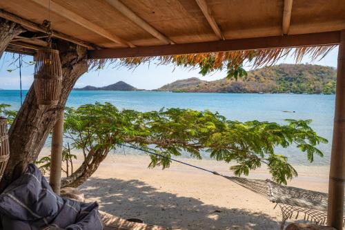 a hammock on a beach with a view of the ocean at Palmyra Indah Bungalows in Sekotong