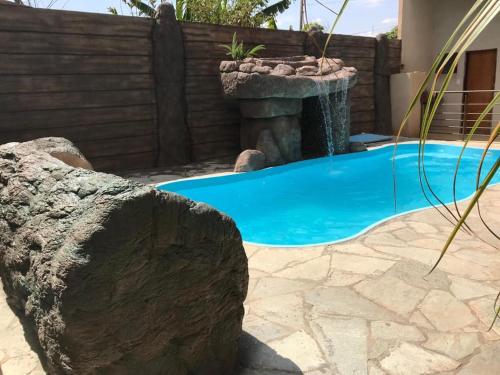 a swimming pool with a water fountain in a yard at Pousada Facincani in Olímpia