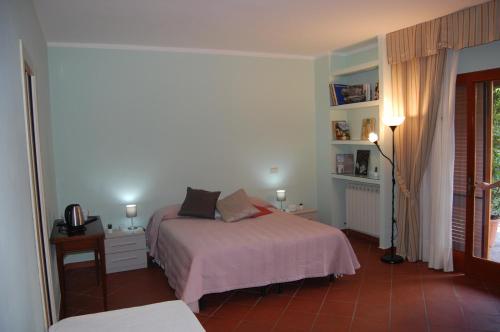 a bedroom with a bed and a table and a window at Affittacamere Loretta in San Giuliano Terme