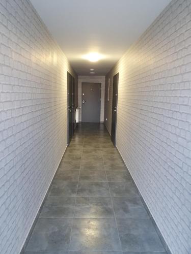 an empty hallway with a white brick wall and a tile floor at Willa "Aparthause" E-Apartamenty in Mielec