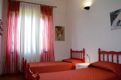 a bedroom with two beds and a window with red curtains at Villa Orrì in Tortolì