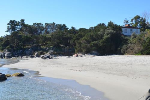 a beach with a white house on a hill at Villa Orrì in Tortolì