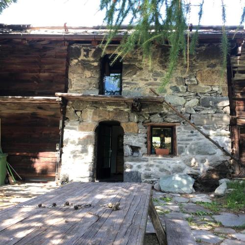 a stone house with a wooden porch and a door at Chalet historique de haut standing in La Tour