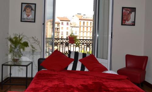 a bedroom with a red bed and a large window at Apartamento Plaza Del Castillo in Pamplona