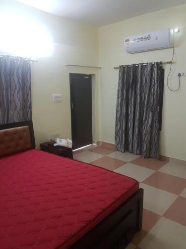 a bedroom with a bed with a red comforter at SM Guest House in Lucknow